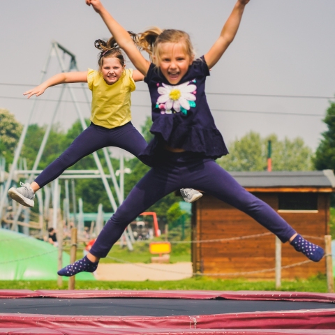 Zwei Mädchen auf Trampolinen auf dem Abenteuerspielplatz